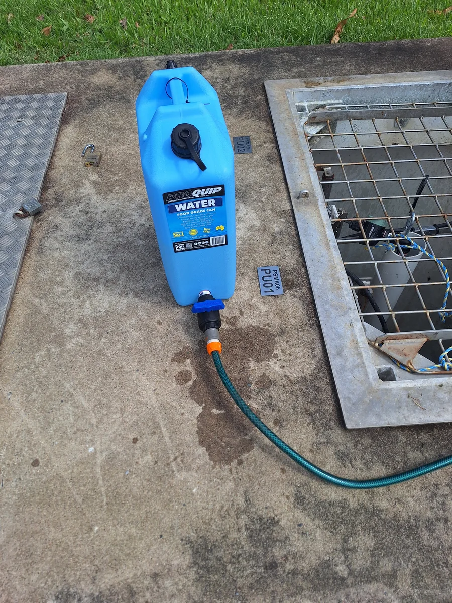 Portable water container and hose beside a grated access opening during site work